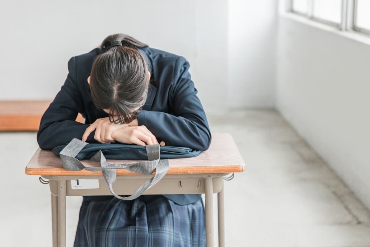 机に突っ伏している女子高生