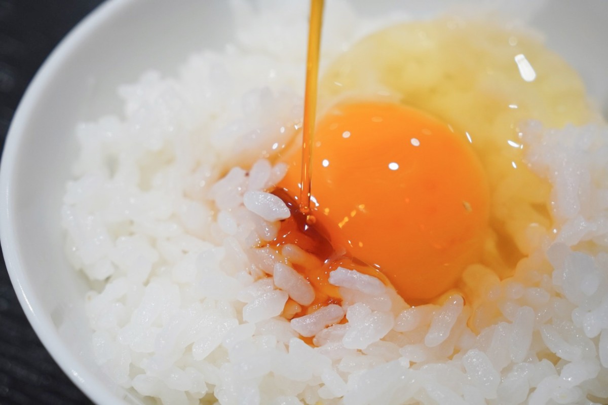 仁多米の卵かけご飯に「しいたけ醤油」をかける様子